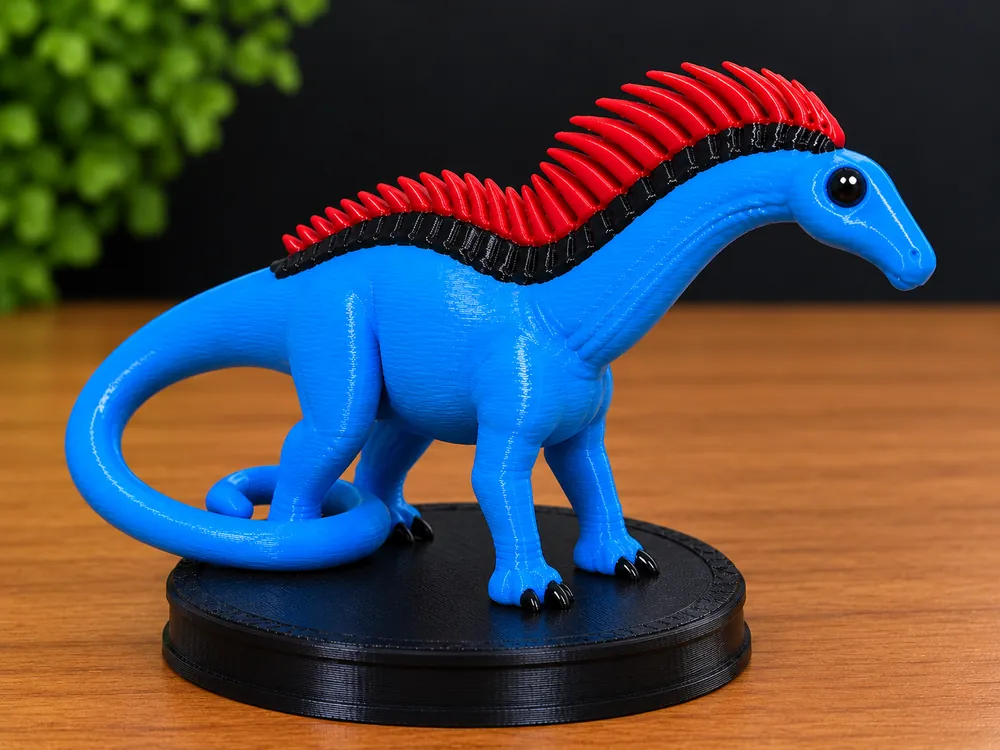 Boneco Amargassauro azul com crista vermelha sobre base preta, em cima de uma mesa de madeira